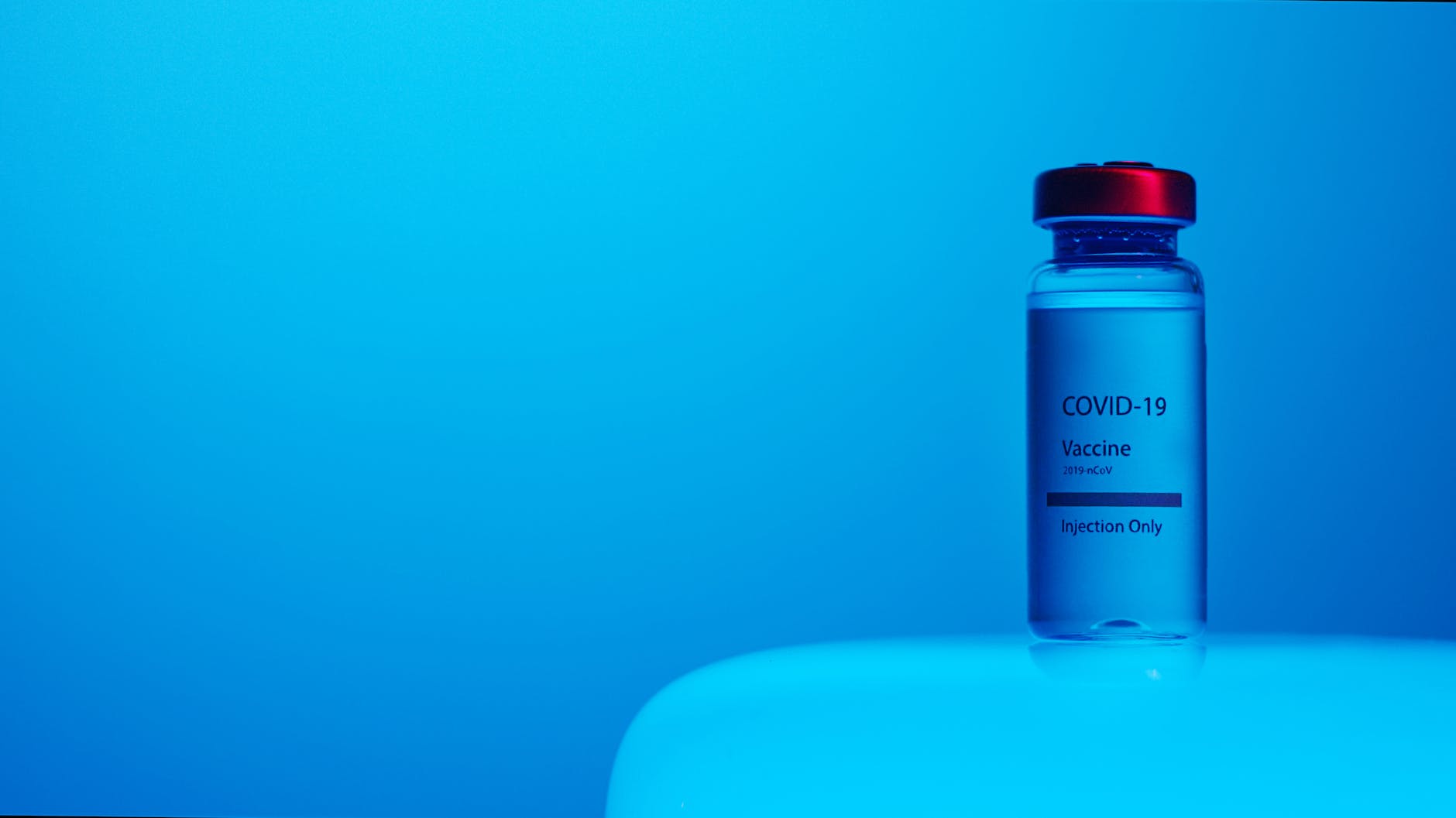 closeup of COVID-19 vaccine vial on blue background
