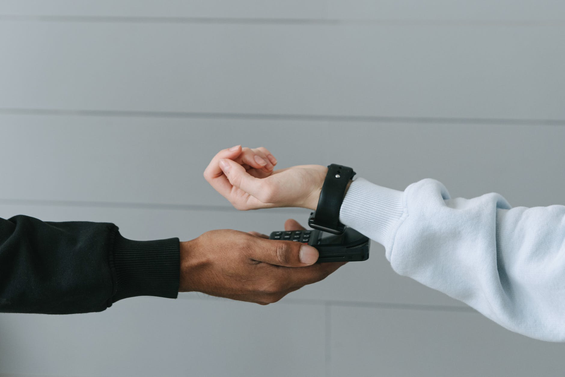 Person paying using a smartwatch: two arms coming together.