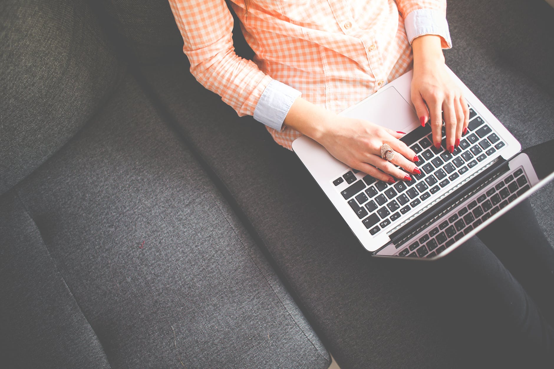 Person sitting on gray sofa while using Macbook