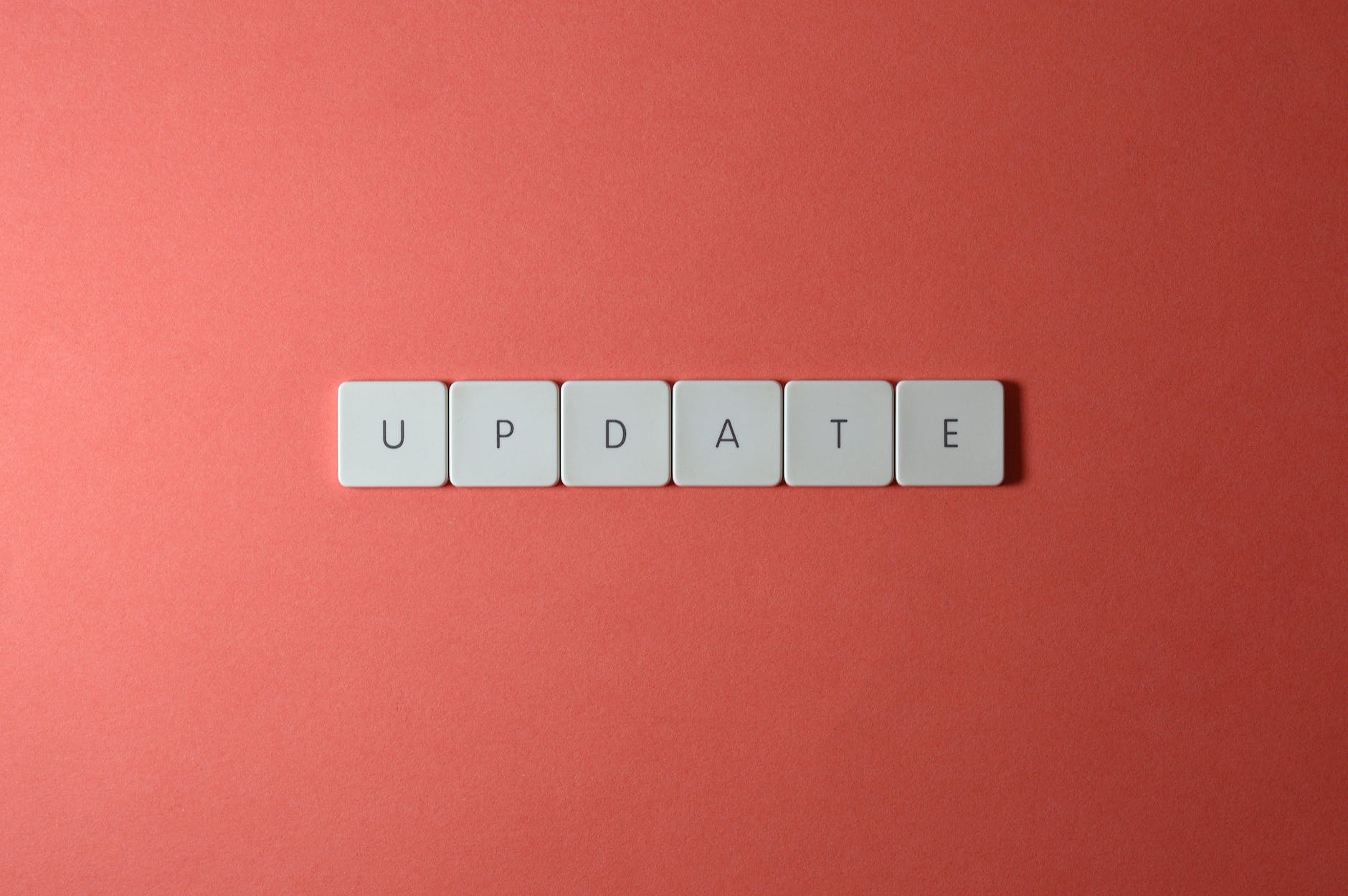 Close-up shot of keys on a red surface spelling "UPDATE"