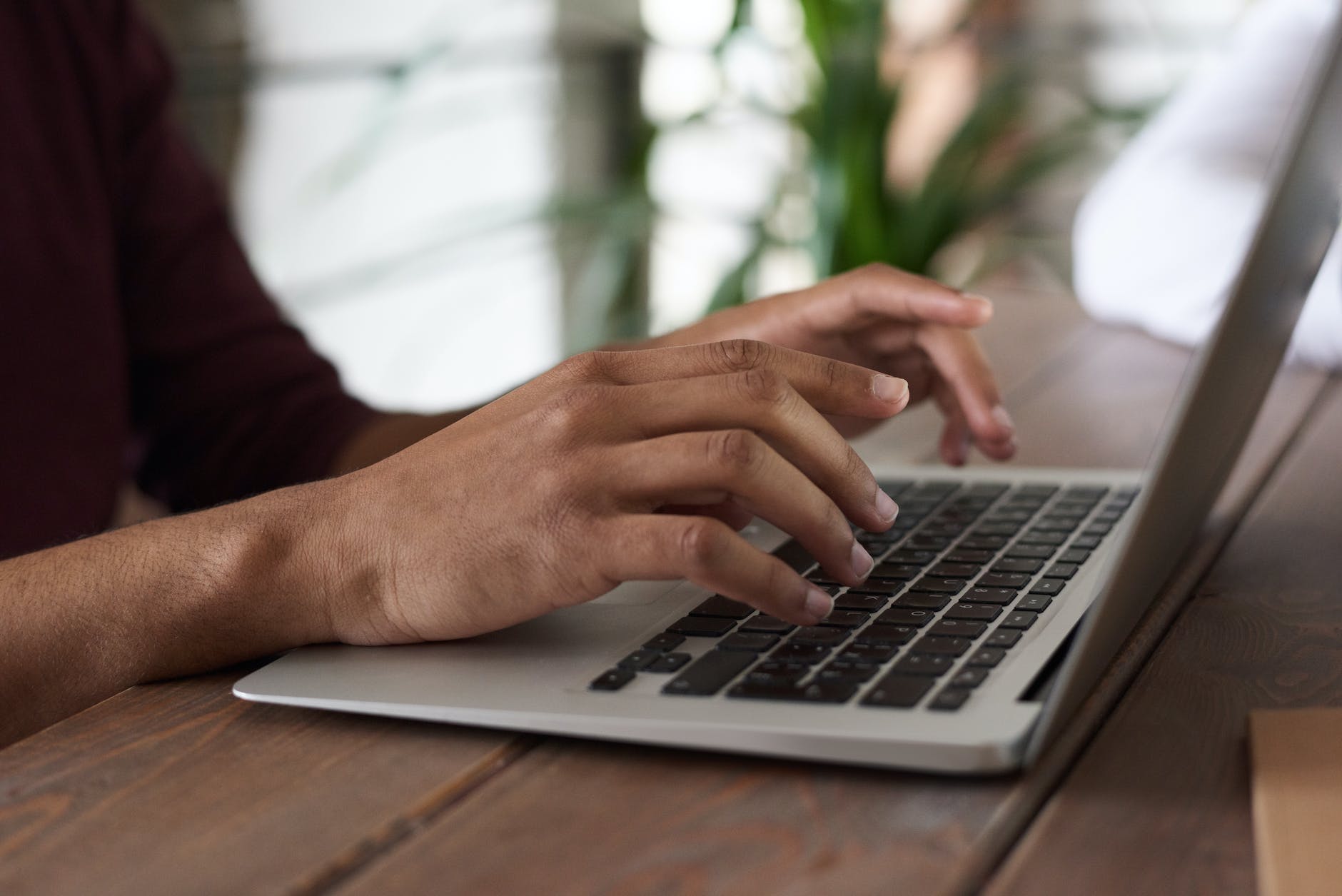 person using Macbook Pro. Hands on keyboard. Dark skin tone.