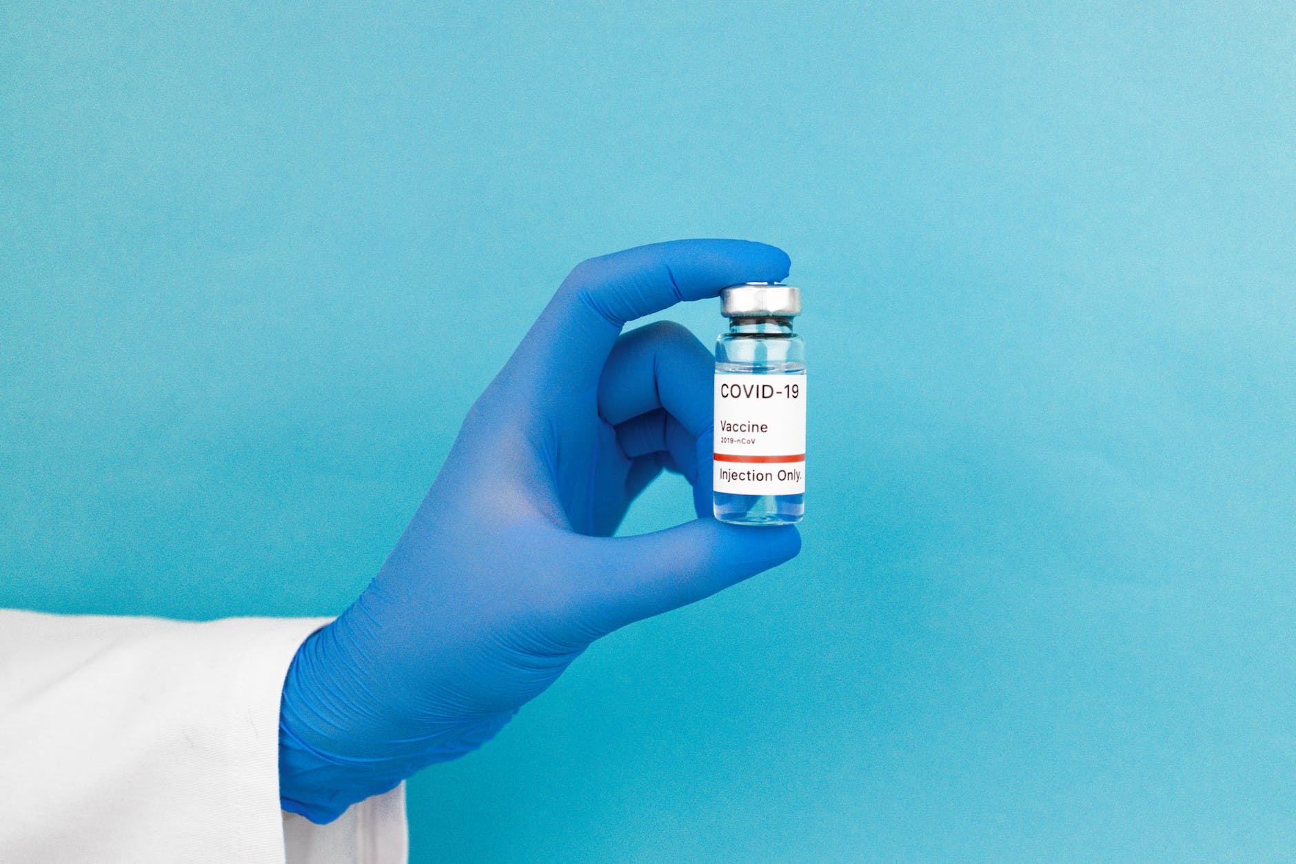 person holding white labeled bottle "COVID-19 Vaccine."