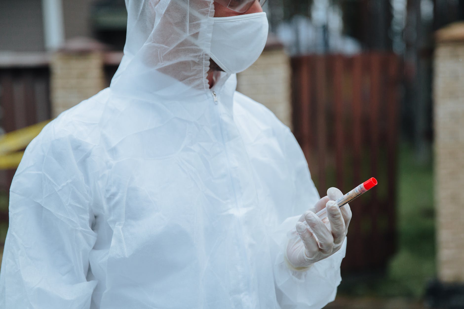 a person holding a vacutainer and wearing protective gear and gloves.