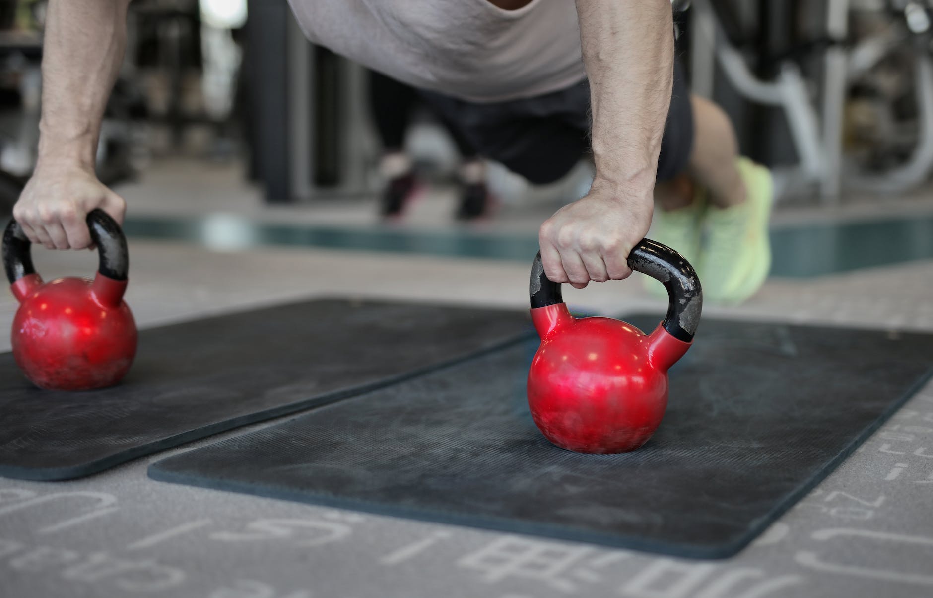 muscular person doing plank exercise on ketterbells