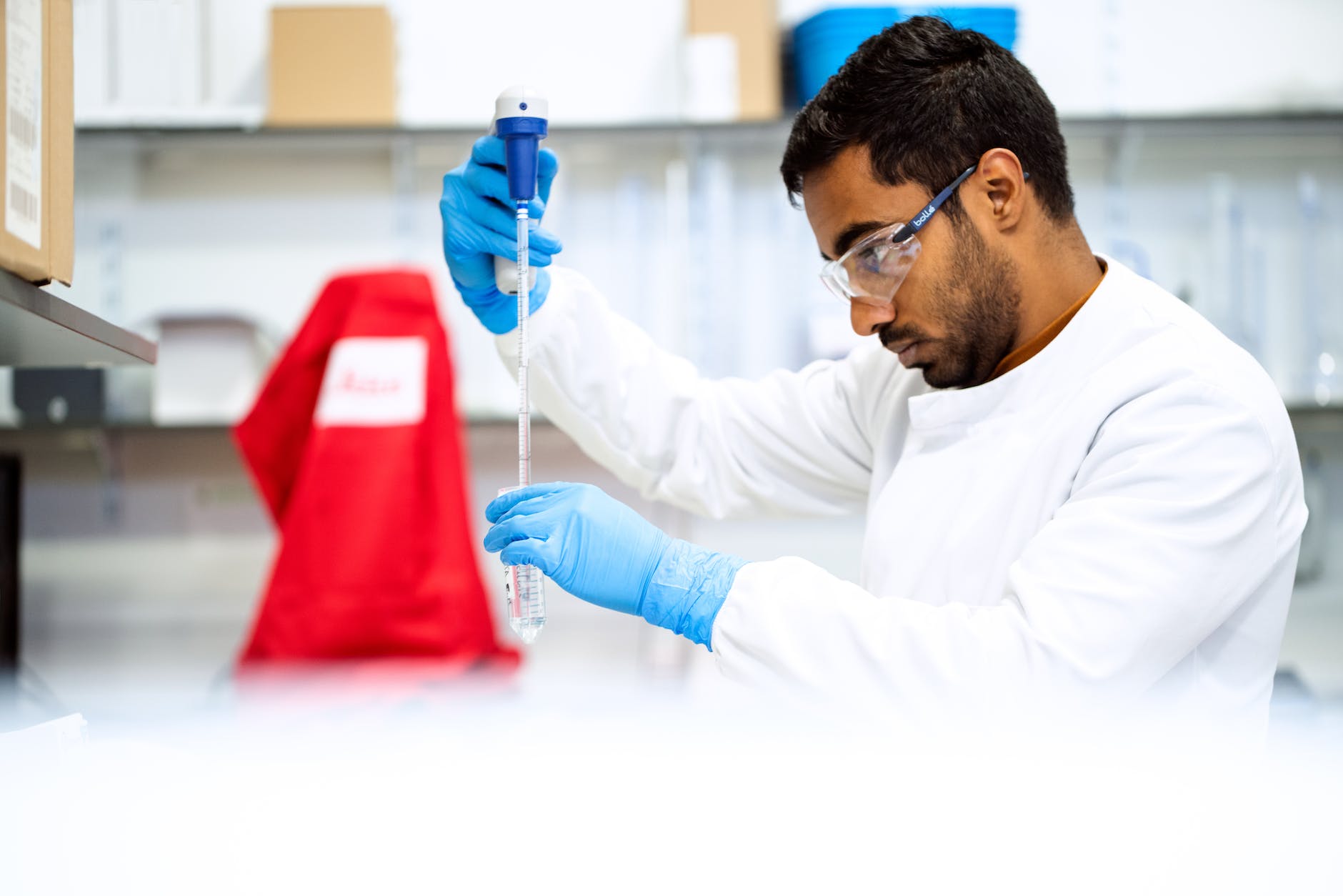 scientist in laboratory pipetting wearing gloves and eye protection
