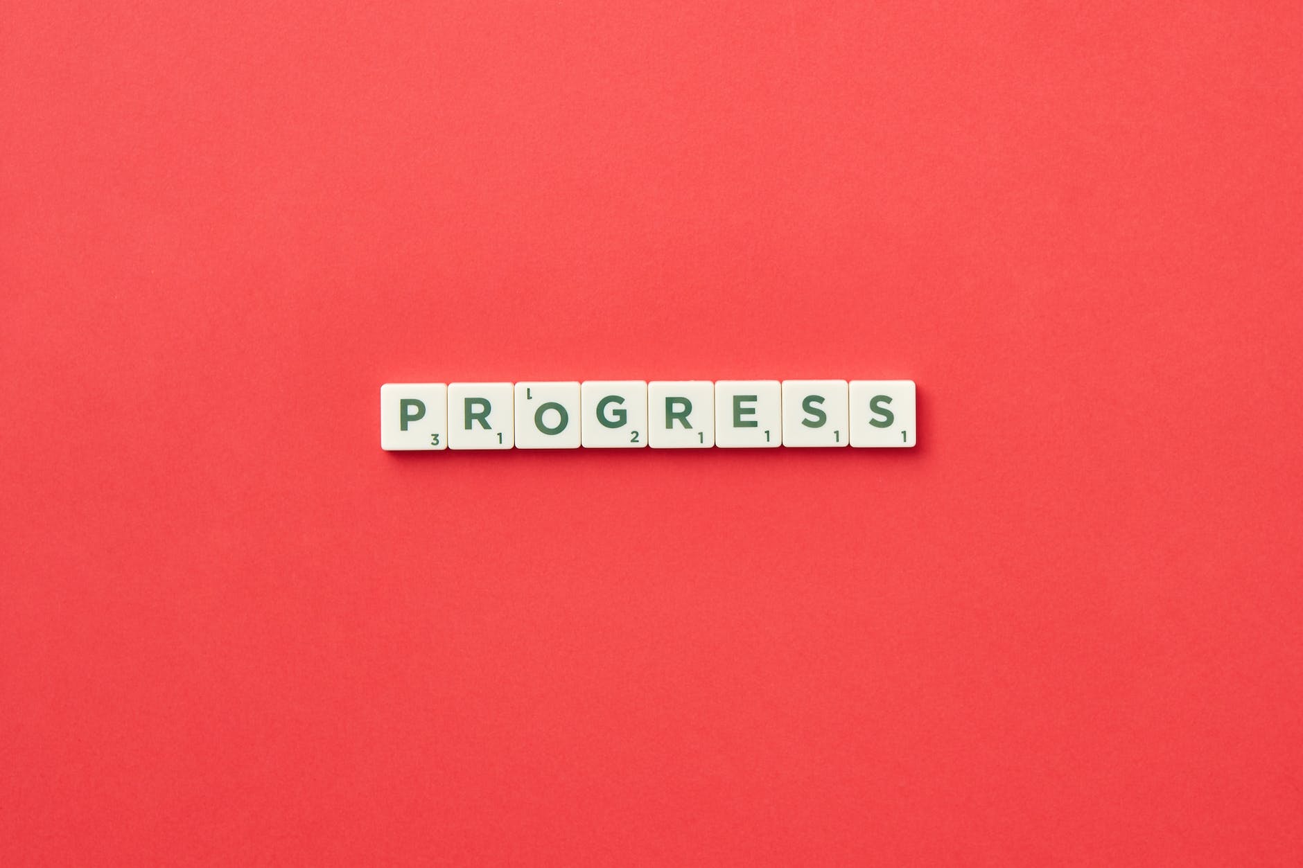 Text on scrabble cards spelling PROGRESS on red background
