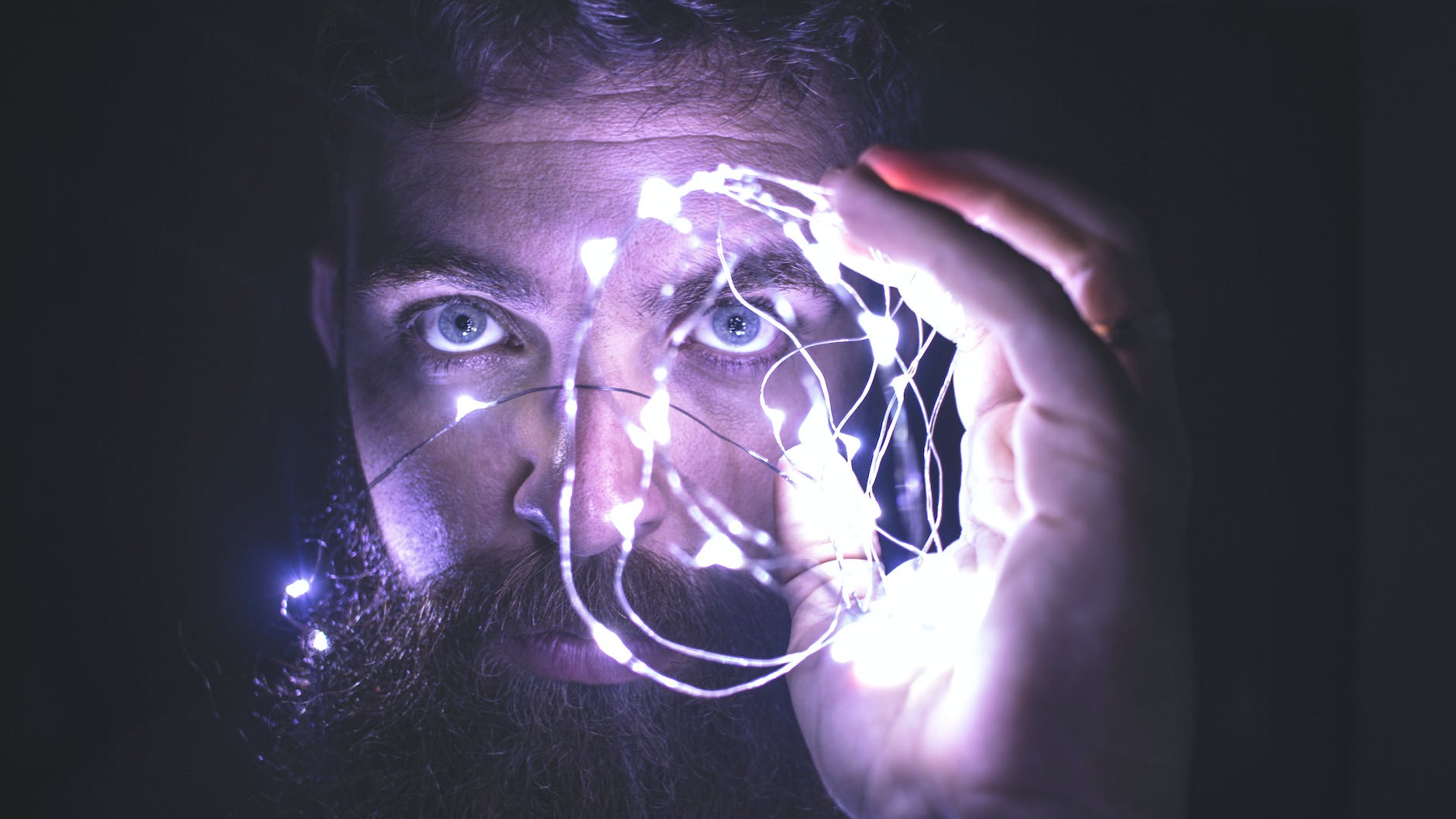 person holding string of lights near face