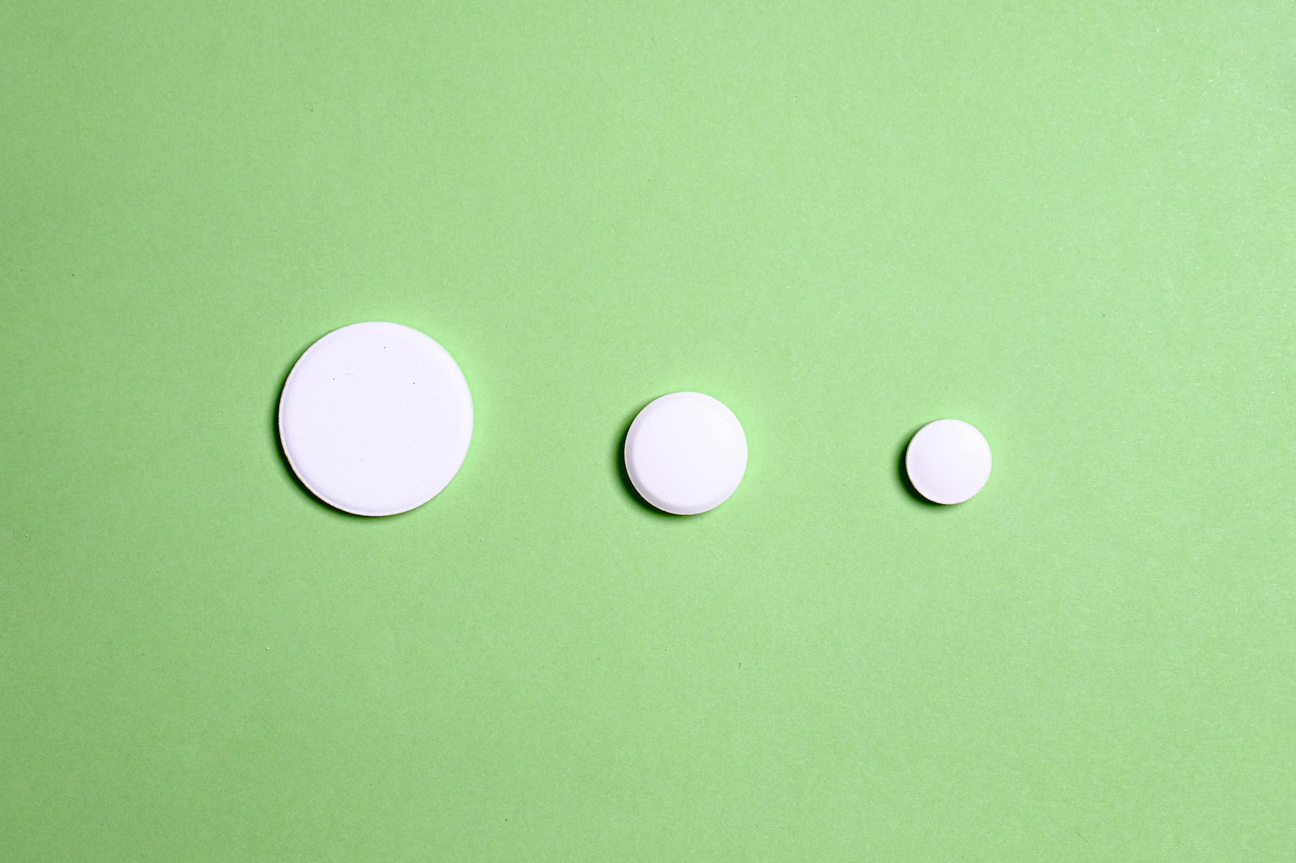 white round medication pills (three) on green surface