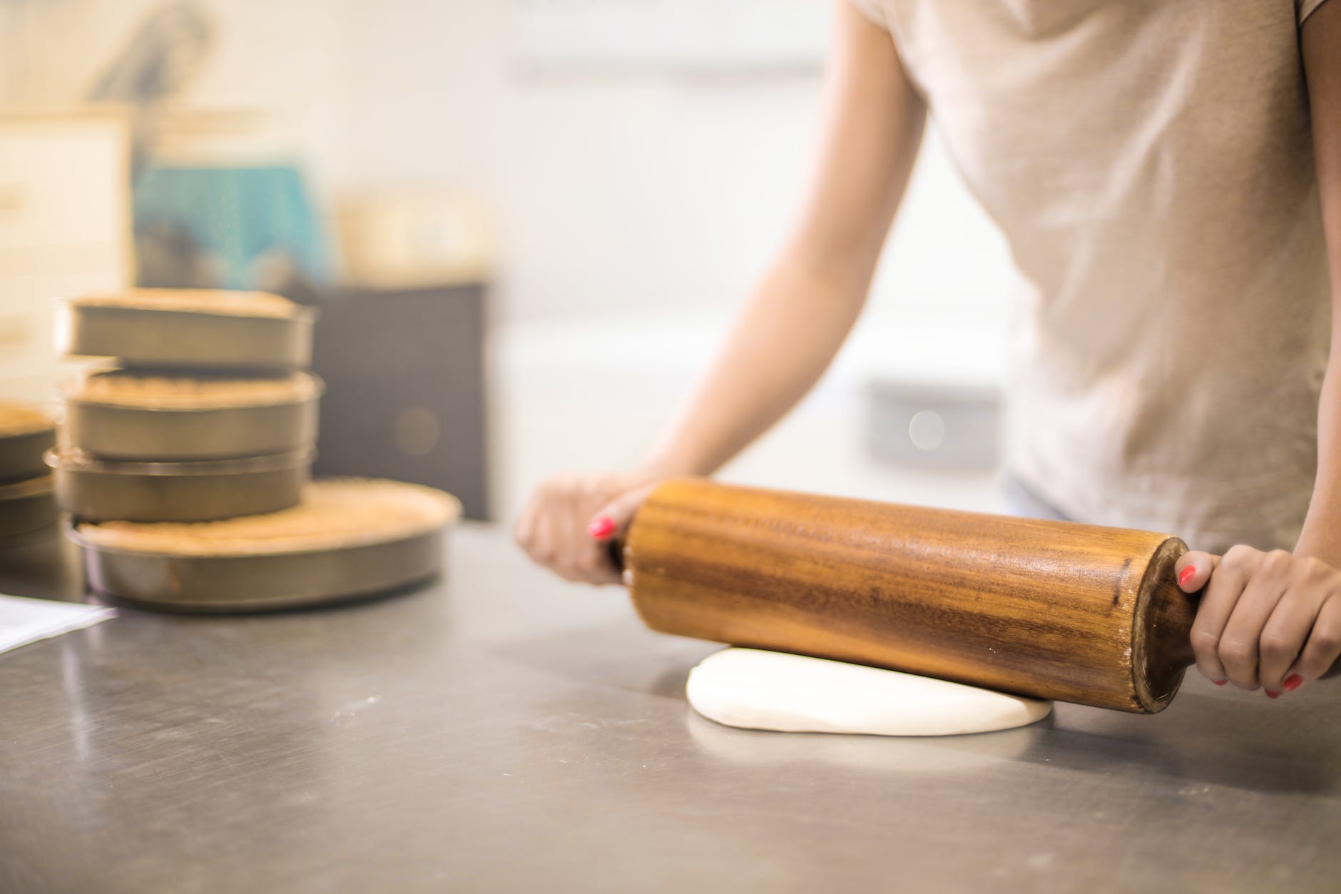 person in white t-shirt rolling a pin in dough