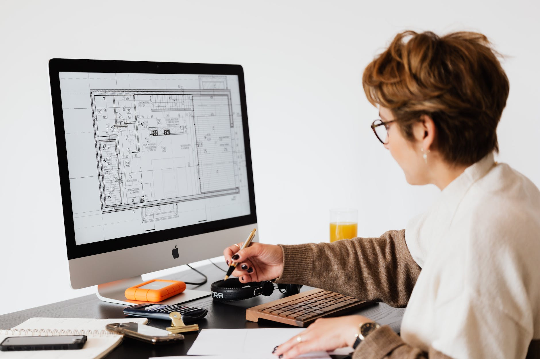 woman concentrating and examining data on a computer screen while taking notes