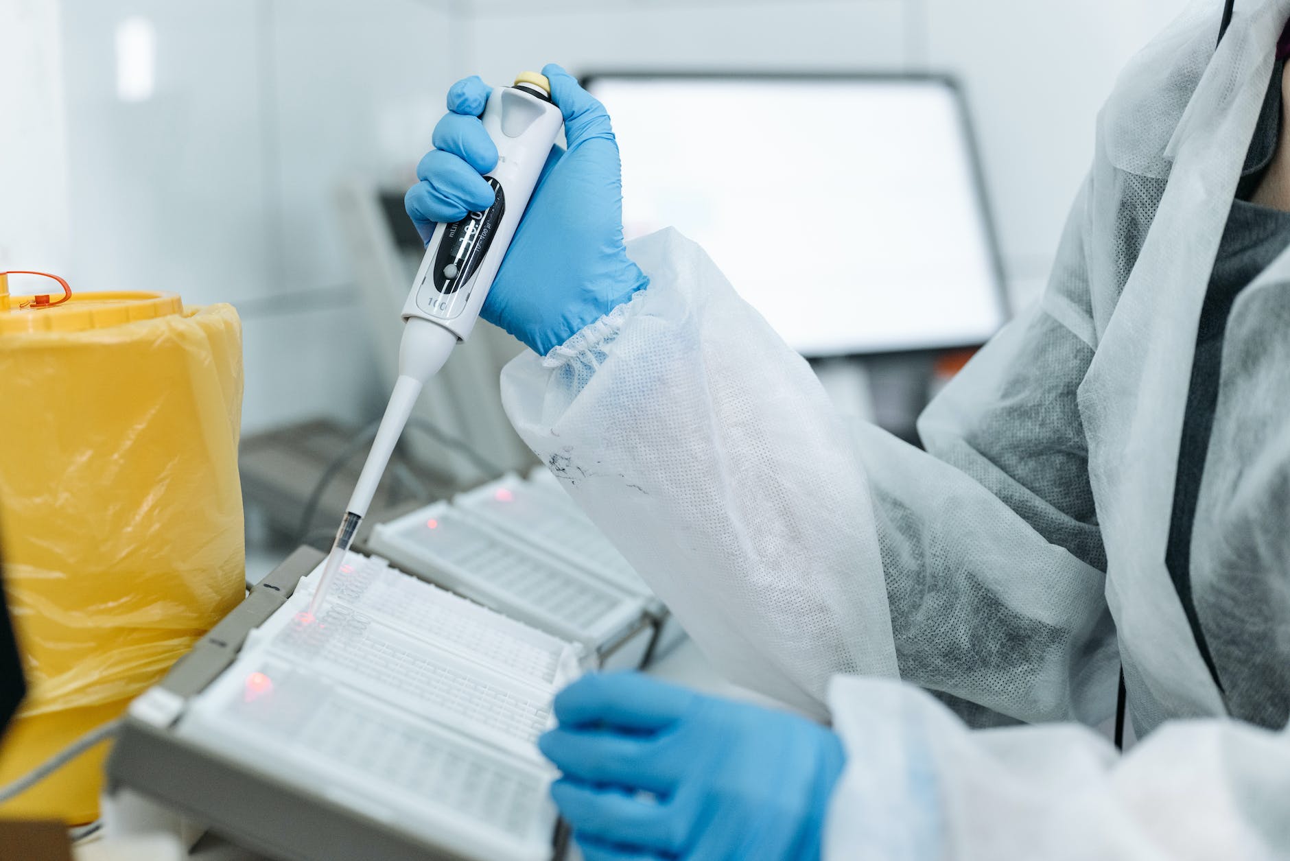 person holding pipette and white 96-well plates