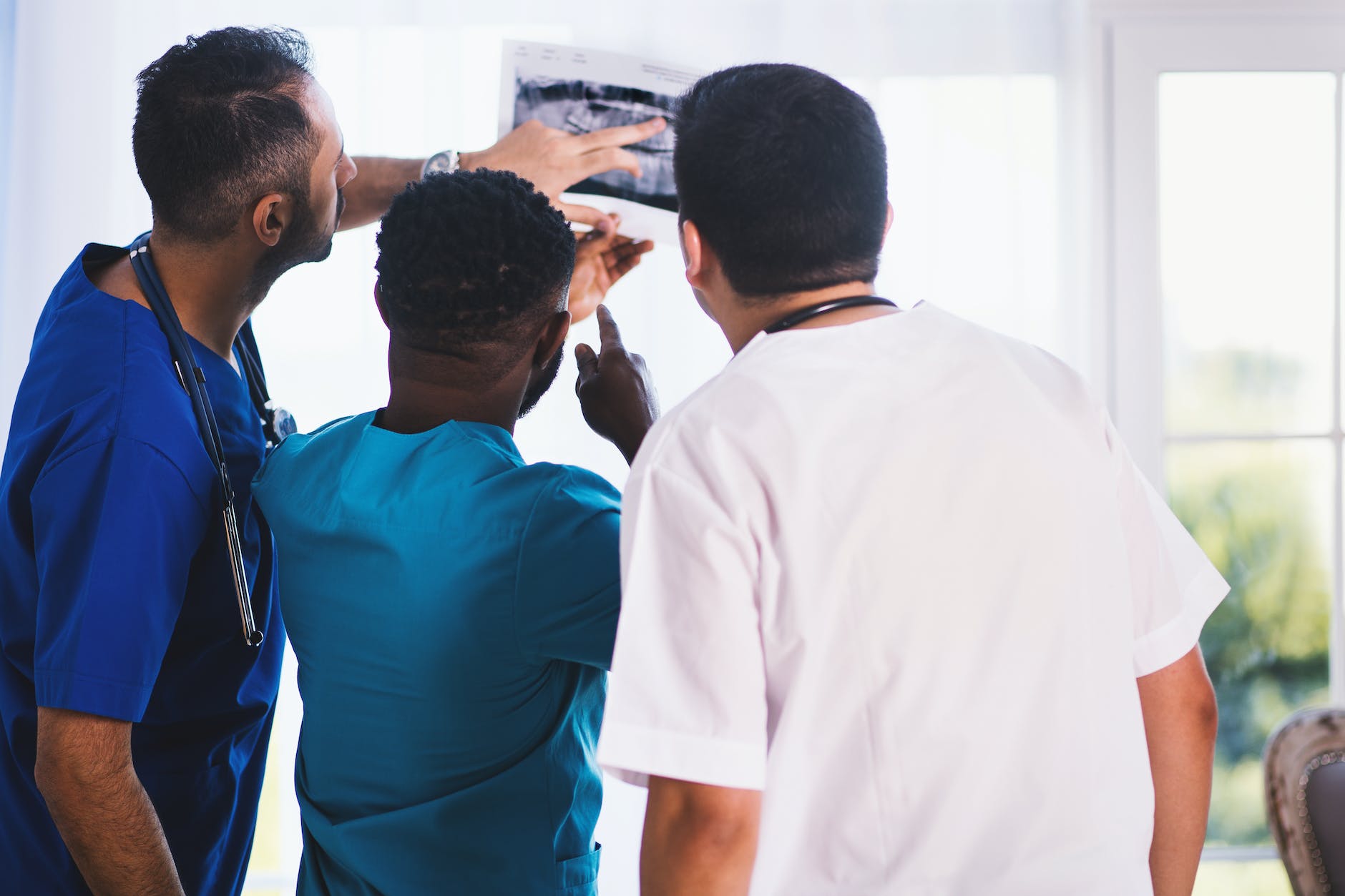 three people looking at X-ray results wearing scrubs