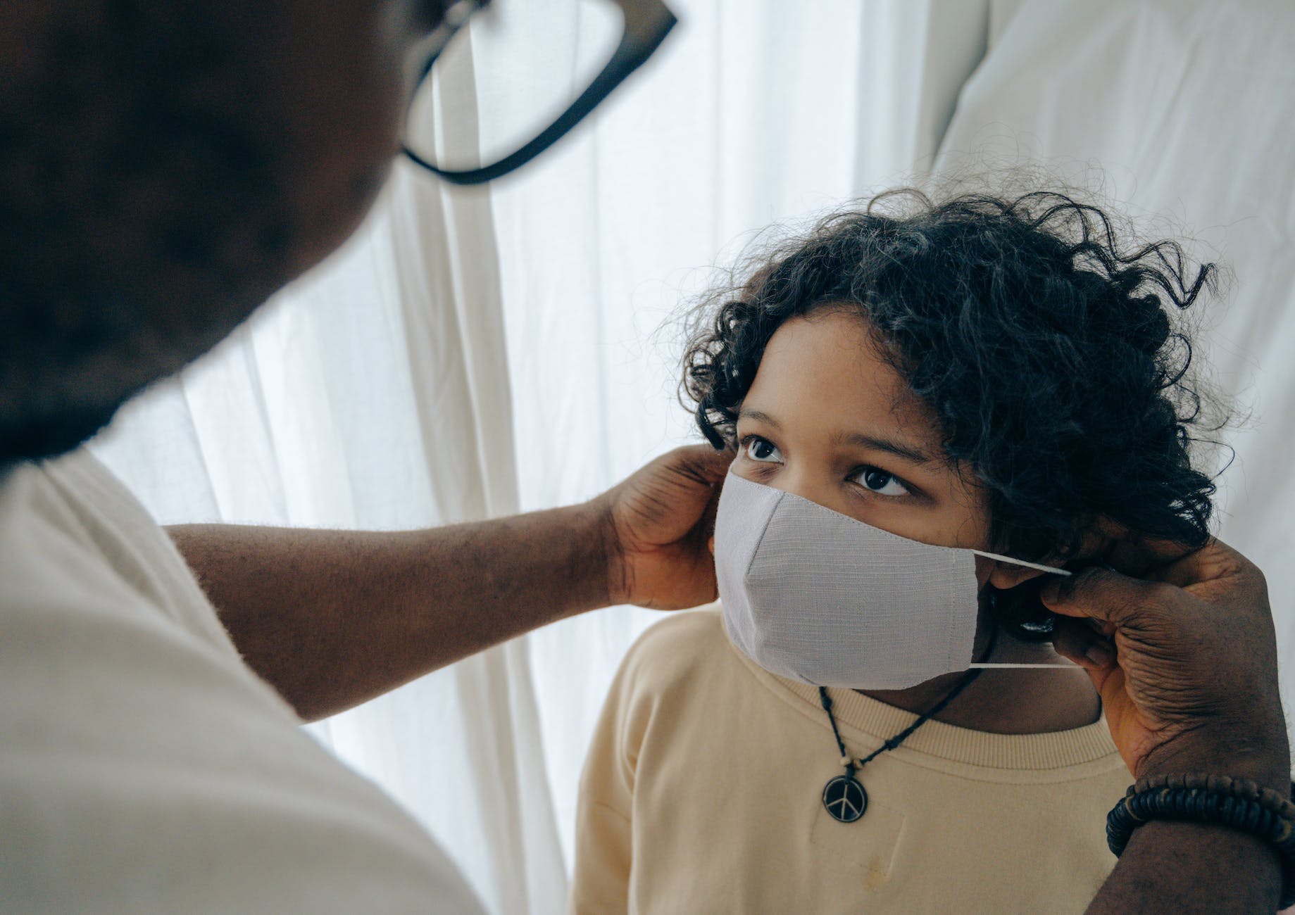 manputting medical mask on face of child