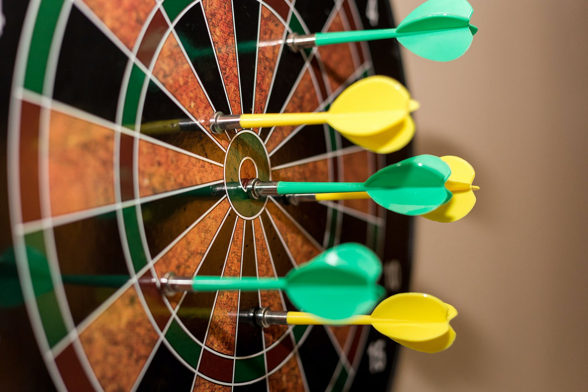green and yellow darts on brown-black dartboard