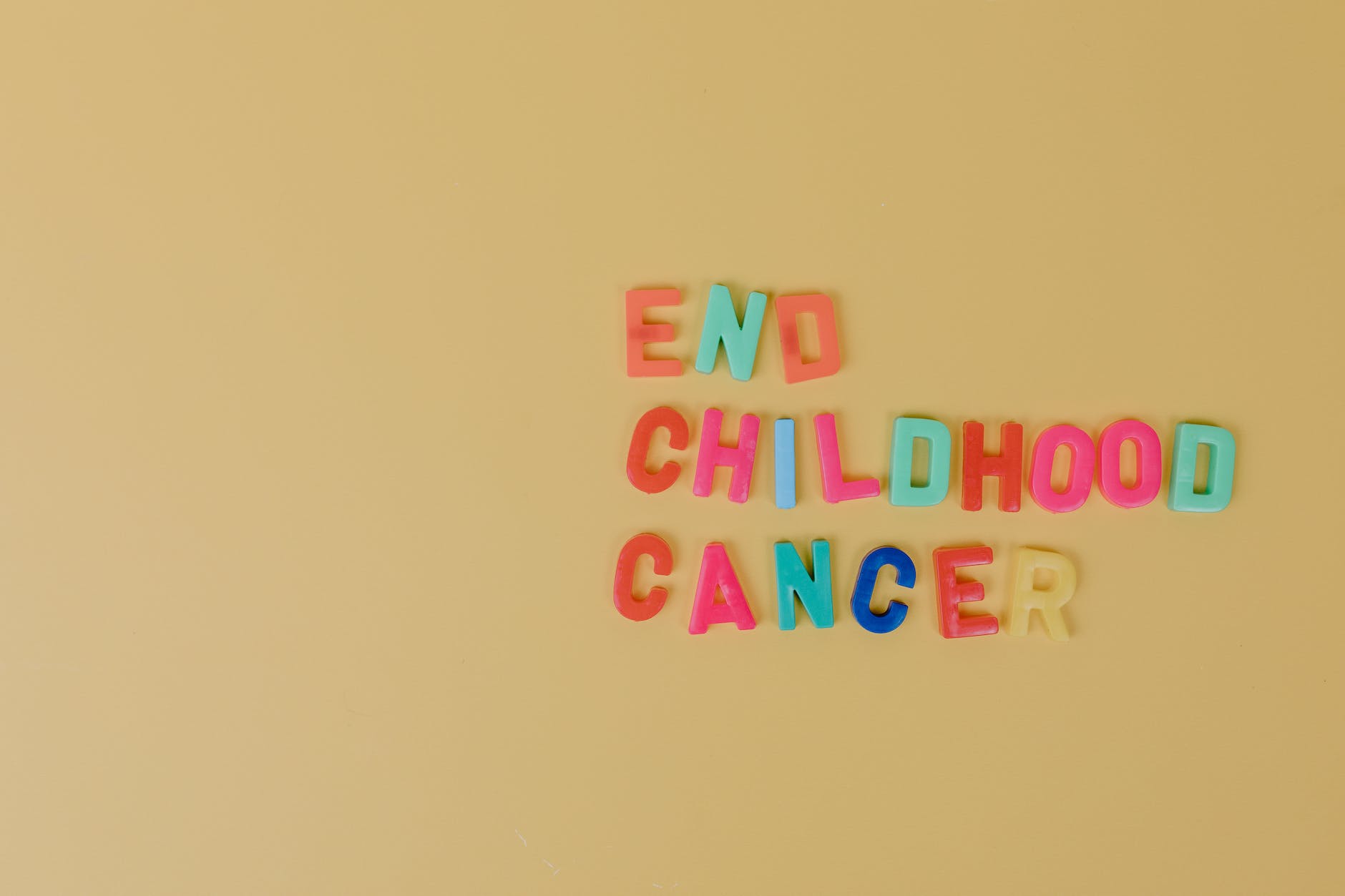 colorful letters on a beige colored surface spelling "End childhood cancer"