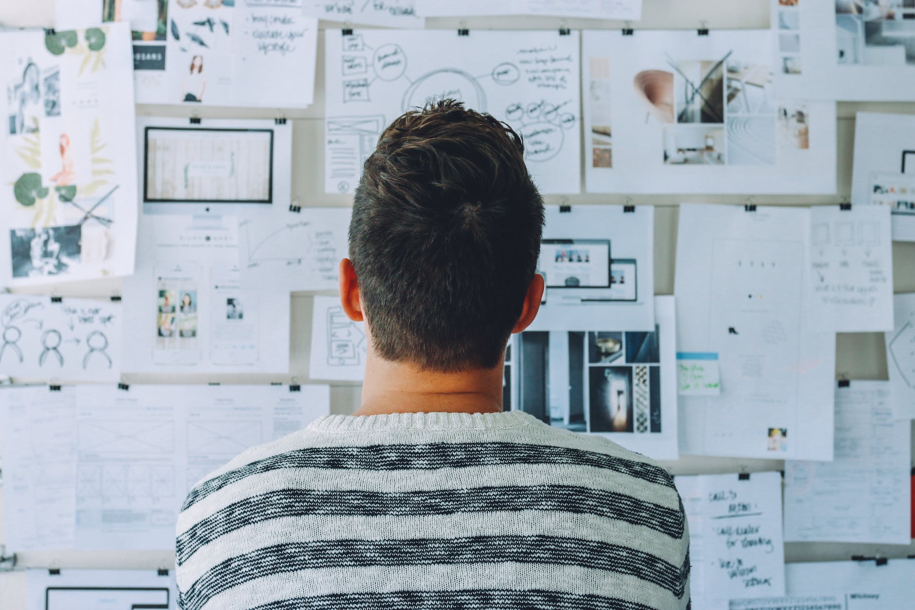 back of person staring at bulletin board with lots of papers and data