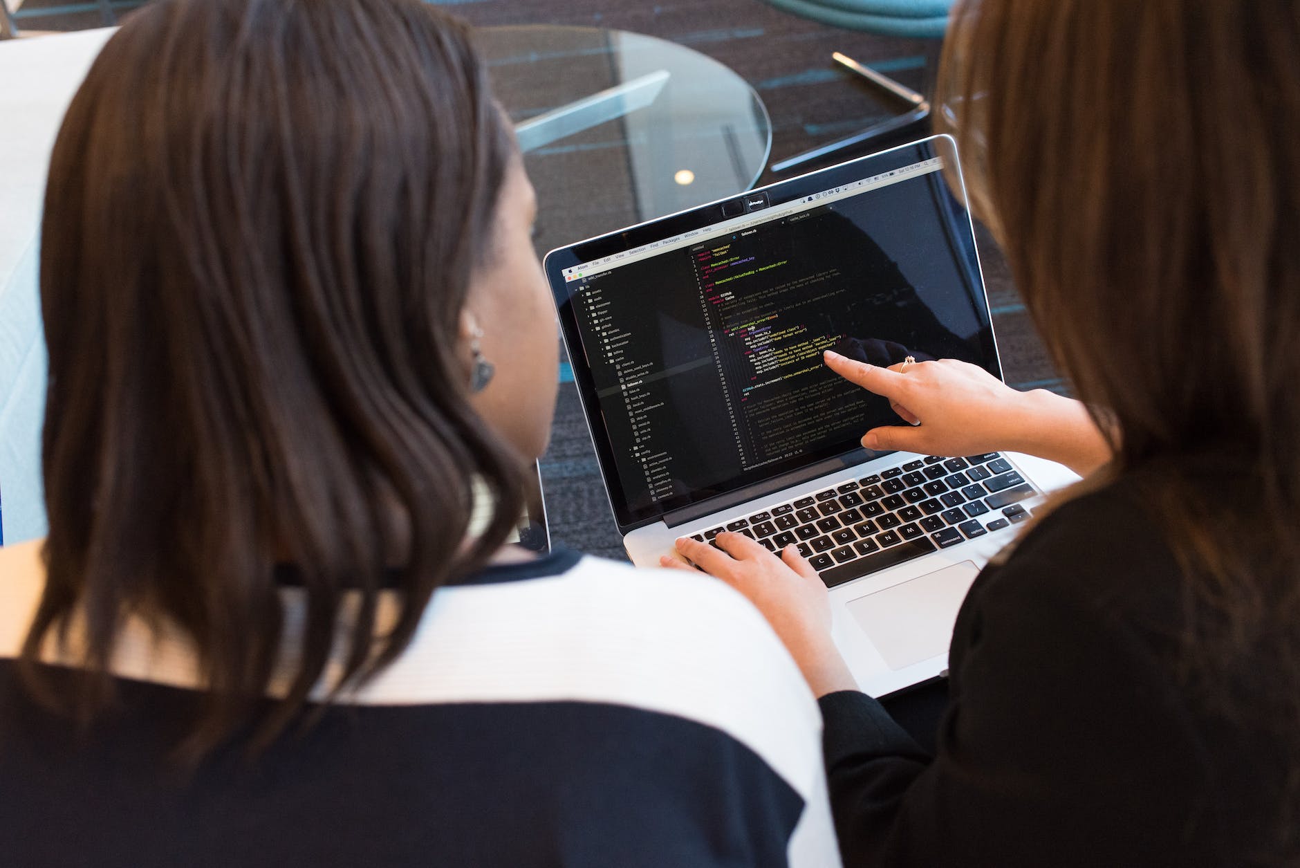 two people working on laptop with one person pointing at screen