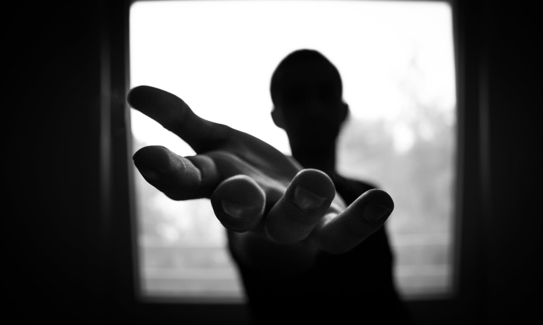 black and white photo of person extending arm and open hand toward camera