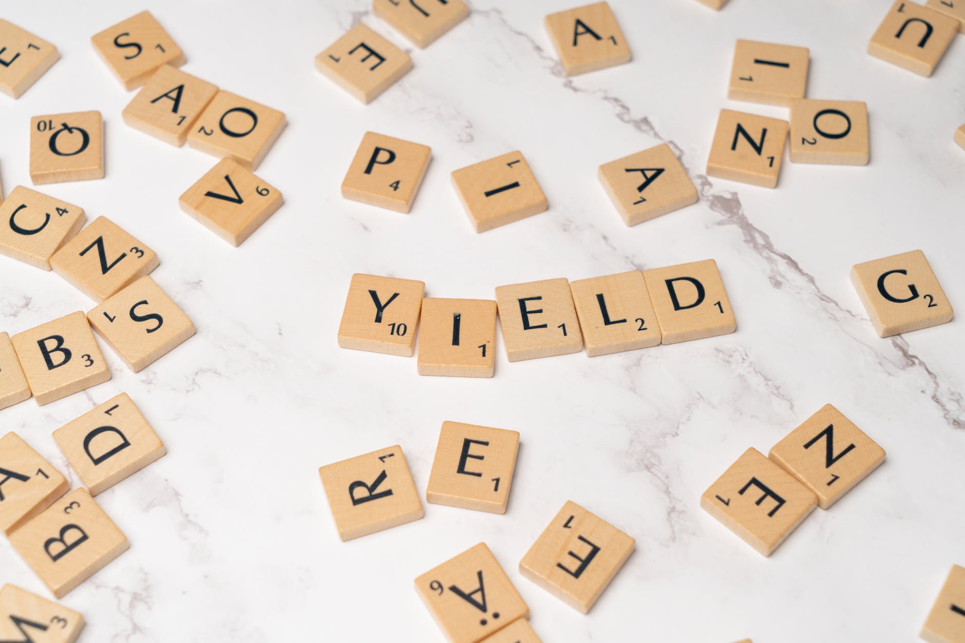scrabble chips scattered on marble counter forming word "YIELD"