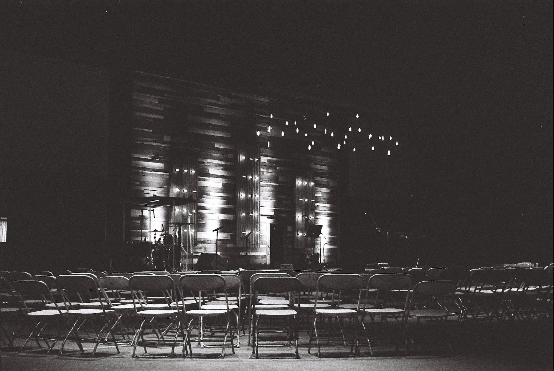 rows of chairs in dark room with stage with rows of lights