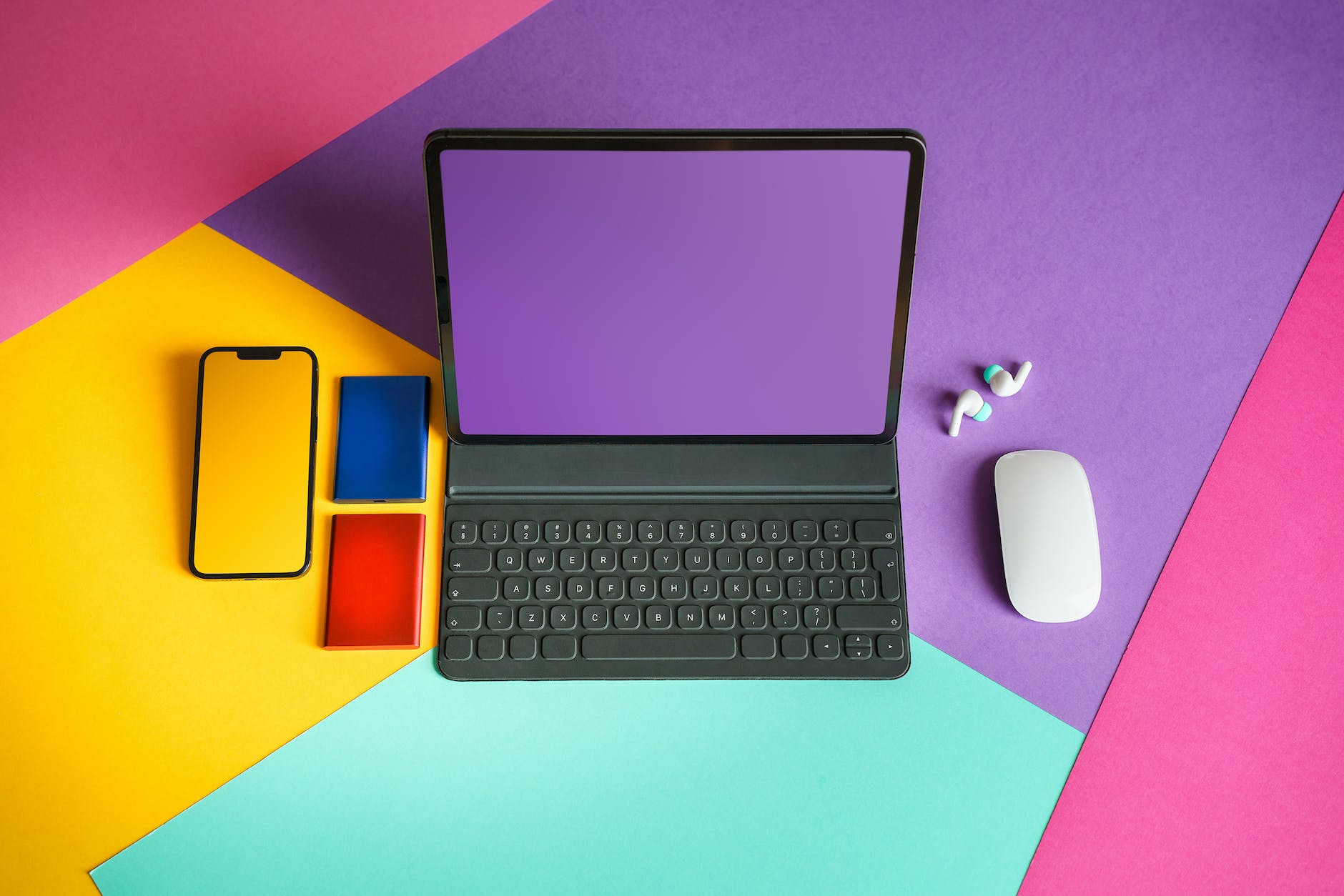 laptop, tablet, and phone devices on colorful table