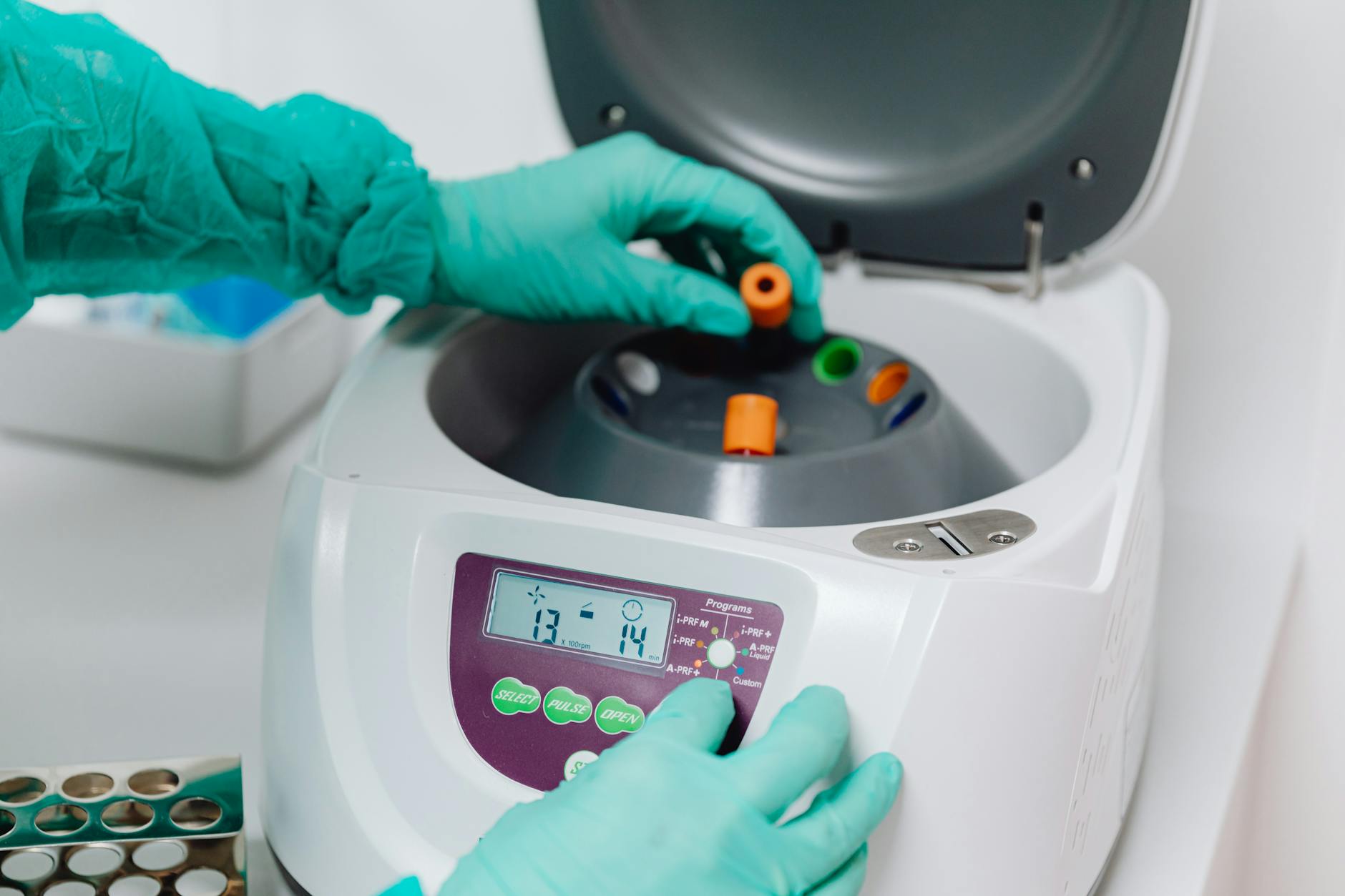 gloved hand putting blood vials into centrifuge