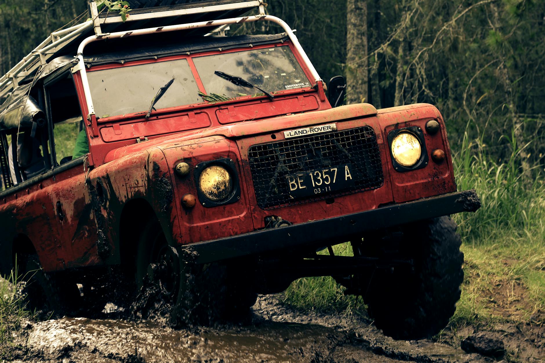 red Land Rover going over hill